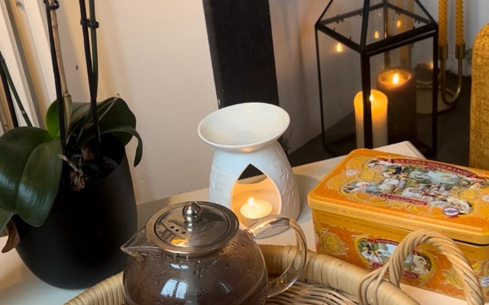 A warm Parisian tea table — orchid, candles, teapot